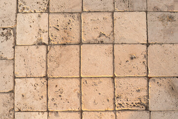 Obraz premium The detail of worn stone paving blocks, showcasing their texture and the subtle color variations due to weathering. The natural light enhances the stones sandy tones