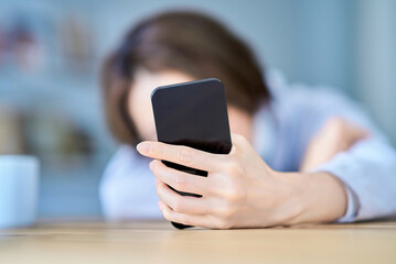 疲れた様子でスマートフォンを操作する女性