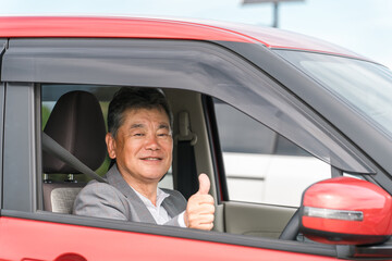 自動車の運転をする笑顔の高齢者ドライバーの男性
