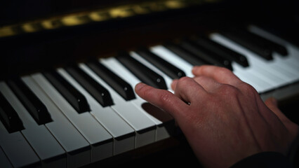 Playing piano only left hand. Media. Close up of person playing musical instrument.