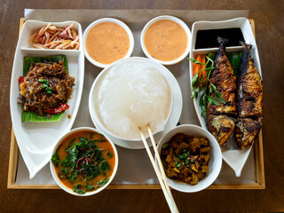 Ambuyat, national dish, local specialty traditional food from Brunei Darussalam. Toop view of Ambuyat set with starch derived from the trunk of a sago palm, on wooden table background.