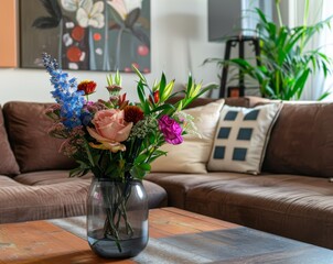 Flowers in vase on wooden coffee table in trendy living room with brown sofa pillows and abstract painting
