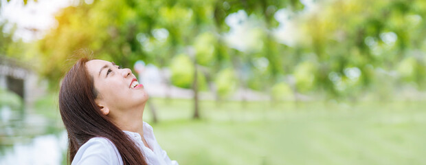 Banner Happy Relax beautiful asian woman smiling face standing in green park outdoors garden. Young...