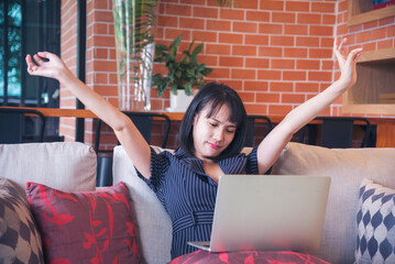 Woman streching arm raised sitting incorrect position home office desk. Back side of young asian...