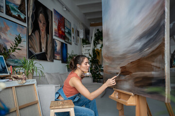 Talented serious woman artist working on abstract painting with careful gentle strokes of small...