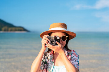 Young woman traveler relaxing and taking picture at the beautiful beach, Summer vacation and Travel concept