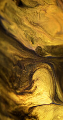 Sparkling ink spill. Glitter fluid texture. Defocused black yellow golden color shimmering sand particles acrylic paint mix emulsion liquid flow abstract art background.