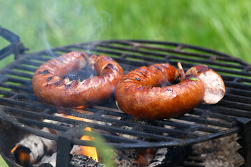 Grilling bratwurst sausages over flaming grill. Bearbeque outdoors. Barbecue Picnic