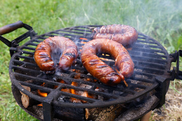 Grilling bratwurst sausages over flaming grill. Bearbeque outdoors. Barbecue Picnic