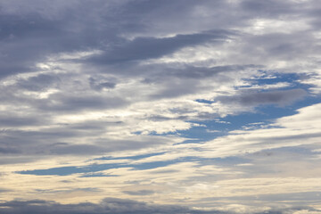 Sun rays shining through dark cloud sky. Black clouds, blue sky, and sun.