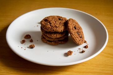 sweet chocolate biscuits on a white plate with a wooden patterned background