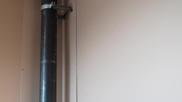 Black pipe running along beige wall in a minimalistic interior