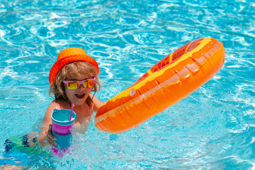Child in swimming pool with inflatable toy ring. Children summer vacation. Summer kids cocktail. Swim for child on float. Beach sea and water fun.