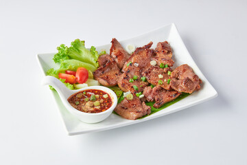 Grilled beef tongue served with a spicy Thai dipping sauce (cayenne pepper, roasted rice, chopped scallions) and fresh salad with tomatoes isolated on white background.