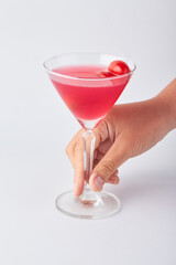 Hand holding Pink daisy cocktail in transparent glass isolated on white background.