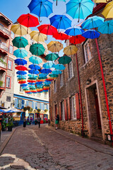 Fototapeta premium Quebec's iconic Umbrella Alley featuring a public art display of colorful parasols suspended high over the Petit Champlain shopping area in Quebec city, the capital of Quebec province,Canada
