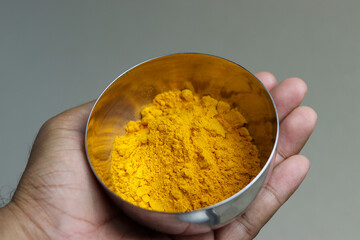 Close up of Turmeric powder in stainless steel bowl.