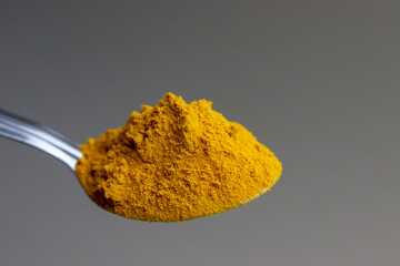 Close up of Turmeric powder in Steel spoon.