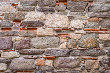 Historic stone wall. rough, old and worn ancient surface. big rock pieces.