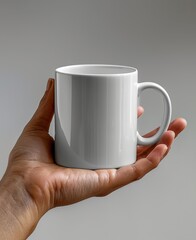 Hand holds white mug against gray background.