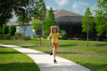 Young kid running and smiling in the park. Active little kid running along street during leisure sport activity. Sporty kid running in nature. Child run. Kids running. Summer sport. Happy childhood.