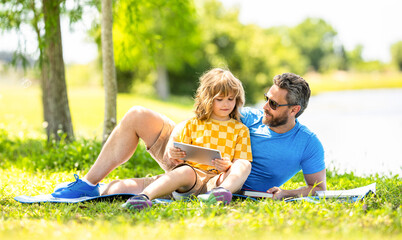 Fototapeta premium son with daddy bonding in summer. family education of daddy and son child. daddy inspire educational journey of his son kid. daddy and son relax in park. childhood school education. outdoor learning