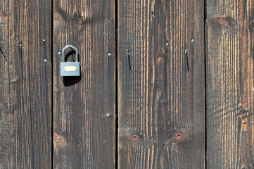 Wood texture of old boards with an open padlock hanging on a nail