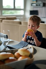 Little toddler sitting at the table and eating bread