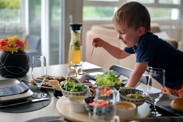 Little toddler at the table choosing dish