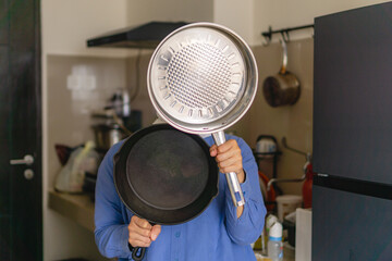 woman holding stainless and cast iron pan, concept of choosing the right pan for cooking