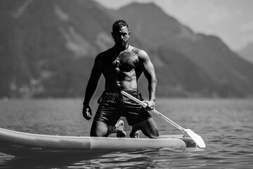 Fit strong muscular model with paddle board. Man paddling on paddleboard. Muscular strong Hispanic...