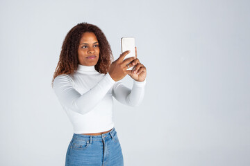 Chica negra afro usando teléfono móvil. Mujer haciendo selfies. Fotografia con móvil....