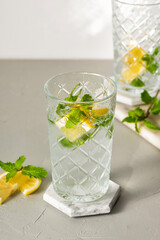 A refreshing summer drink or alcoholic cocktail with ice, mint and lemon on a sunny day. A fresh healthy cold lemonade drink. Sparkling water with lemon