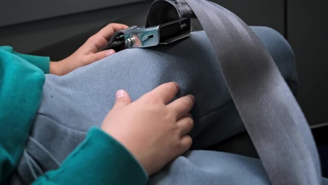 The kid does not fasten his seat belt well. Irresponsible behavior of a child. A passenger buckles up with a seatbelt on the airplane but not well. Irresponsible behavior of a child. Need control. 4K