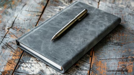 a closed grey notebook and a sleek pen on a worn wooden surface 