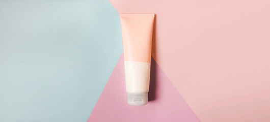 A clean label facial or body cream tube is isolated on a multi-color background. Beauty product mockup. Wellness packaging. Banner for Branding