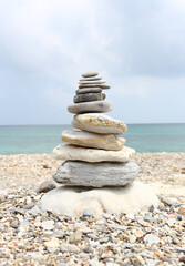 Sandstone are stacked into a pyramid shape on sea and cloud background and copy space.