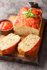 Homemade meatloaf or terrine with mix of chicken and turkey meat glazed with ketchup closeup on the wooden board on the table. Vertical