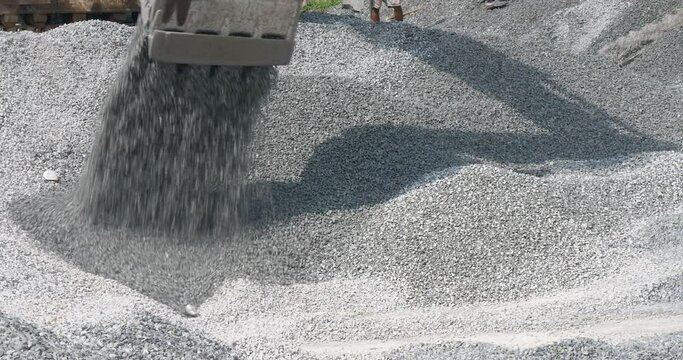 bulldozer dumping a pile of gravel onto an existing pile