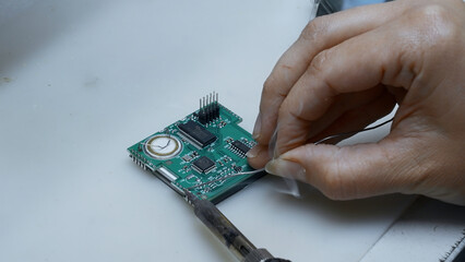 Close up of engineer does computer motherboard soldering. Creative. Painstaking work of soldering a chip.