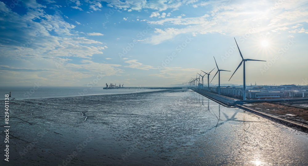 Wall mural Wind power station by the sea at sunset