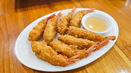 Crispy breaded shrimp. Deep-fried crispy shrimp with sweet sauce on in plate on table. Prawns with dipping sauce. Bowl of shrimp tempura with sauce.