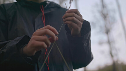 Close-up of man holding straw in forest. Stock. Young man walks in forest and tears up grass. Man picked grass out of boredom while walking in forest