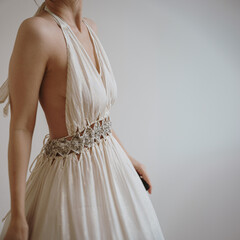 Beautiful white woman wearing elegant neutral creamy beige evening dress over white wall. Aesthetic...