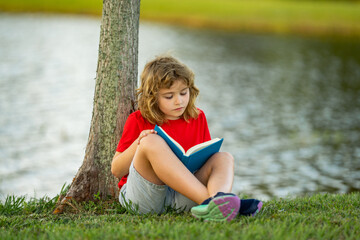 Child with a book. Early education for kids. Summer vacation with book. Outdoor homework. Summer camp with book. Kids learning and education concept. Kid sitting on grass and reading a book.