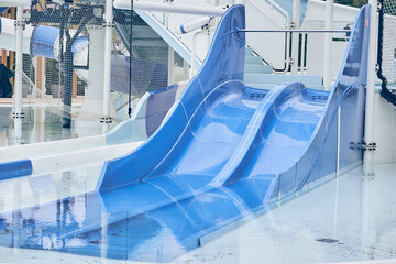 A water park, a bright blue slide with a swimming pool. A water park without people on a summer afternoon in the morning with space to copy. High quality photo