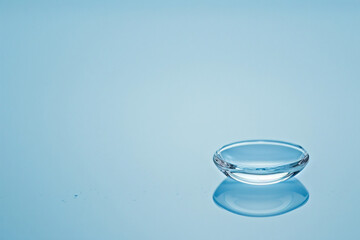 a clear contact lens on a blue surface