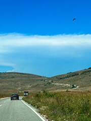 Winding road through mountain landscape, gentle distant mountains, sunny sky