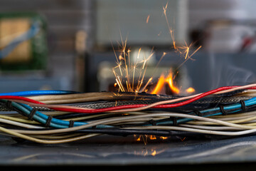 Flames, sparks, smoke between electrical cables, closeup. Short circuit in the twisted wires from...