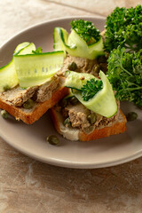 Open sandwiches with pate, cucumber, capers, and parsley.
